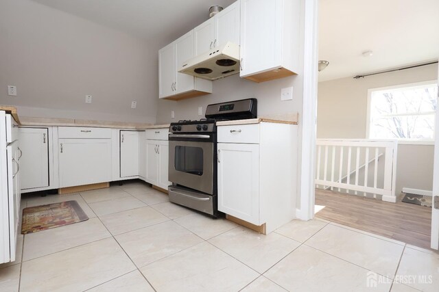 kitchen with light tile patterned floors, gas stove, and white cabinets