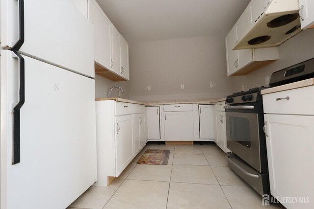 kitchen with white cabinetry, stainless steel gas range oven, white fridge, and light tile patterned floors