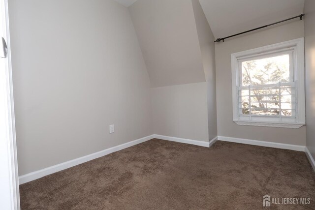 additional living space featuring vaulted ceiling and dark carpet