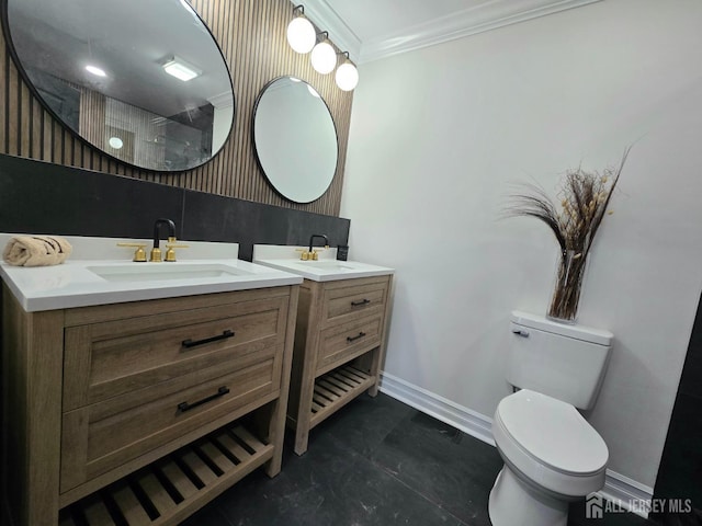 bathroom featuring ornamental molding, toilet, baseboards, two vanities, and a sink