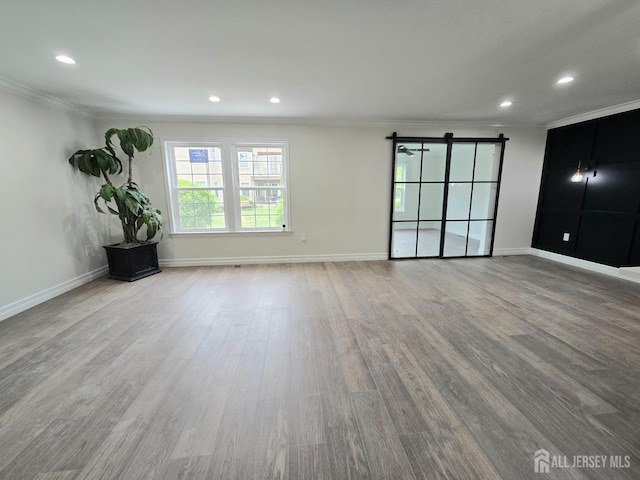 spare room with crown molding, plenty of natural light, and wood finished floors