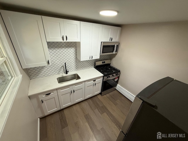 179 Buckelew Ave Unit A, Jamesburg, NJ 08831 - kitchen featuring appliances with stainless steel finishes, baseboard heating, light countertops, dark wood-style floors, and backsplash