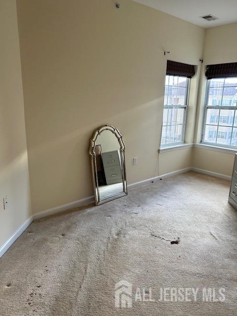 carpeted spare room featuring visible vents and baseboards