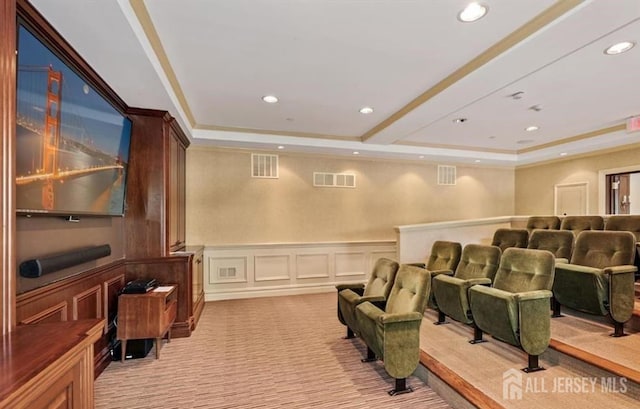 cinema room featuring a decorative wall, light carpet, a tray ceiling, and visible vents