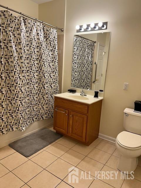 bathroom featuring toilet, shower / bath combo with shower curtain, vanity, tile patterned flooring, and baseboards