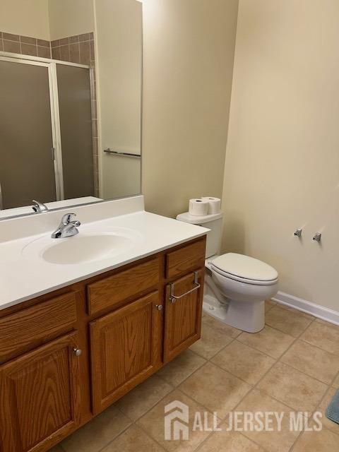 bathroom with baseboards, toilet, tile patterned floors, vanity, and a shower stall