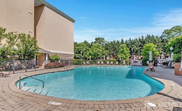 pool with a patio area and fence