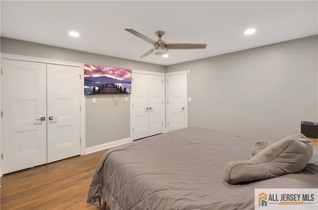 bedroom featuring hardwood / wood-style flooring, multiple closets, and ceiling fan