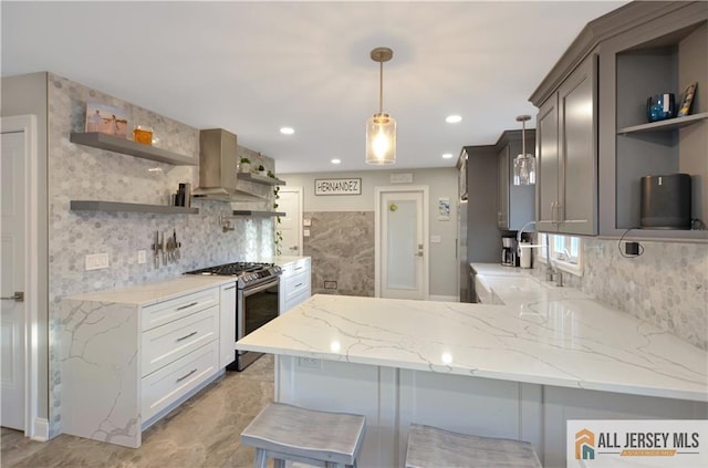 kitchen featuring stainless steel gas stove, ventilation hood, white cabinets, a kitchen bar, and kitchen peninsula