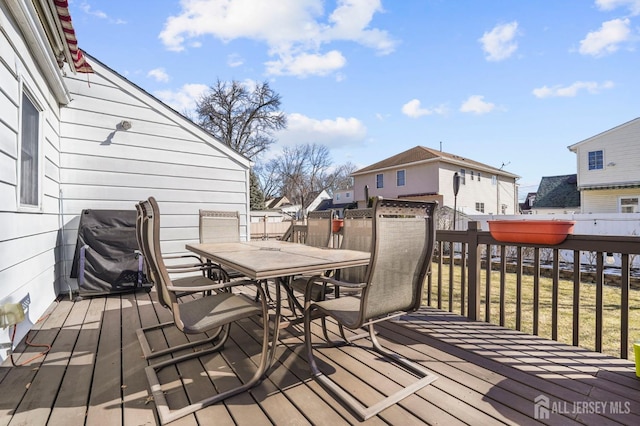 deck with a residential view, outdoor dining area, and grilling area