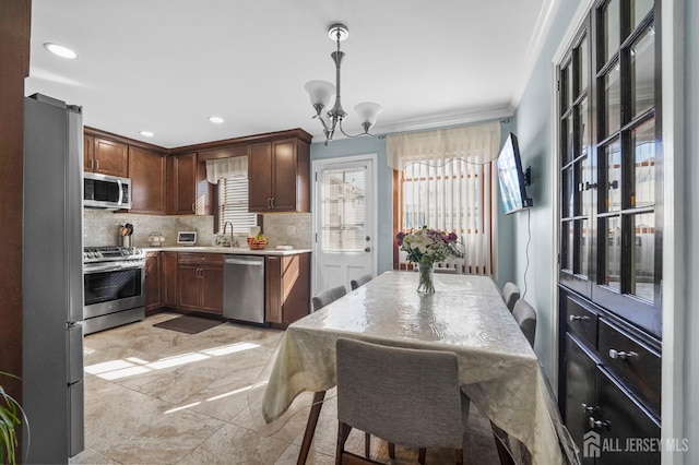 kitchen featuring a chandelier, light countertops, backsplash, stainless steel appliances, and pendant lighting