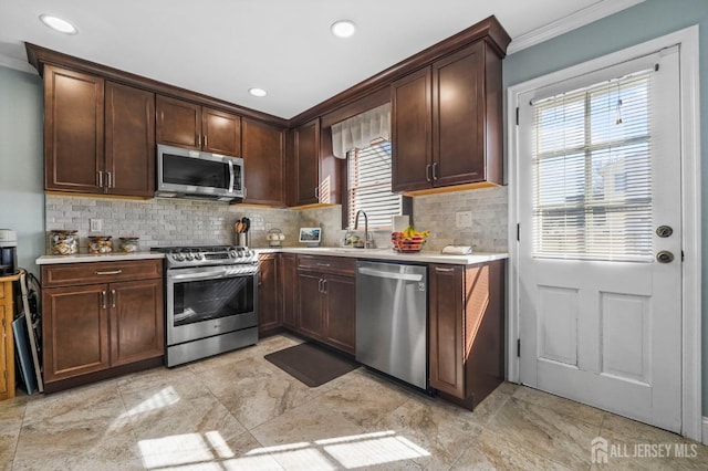 kitchen with light countertops, decorative backsplash, a sink, and stainless steel appliances