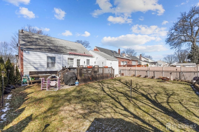 back of house featuring fence, a wooden deck, a residential view, and a lawn