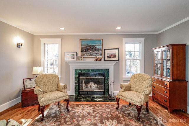 sitting room featuring a tile fireplace, wood finished floors, baseboards, and ornamental molding