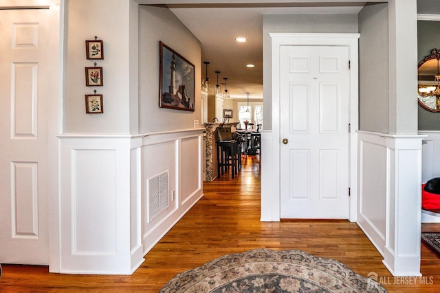 hallway with visible vents, recessed lighting, a wainscoted wall, and wood finished floors