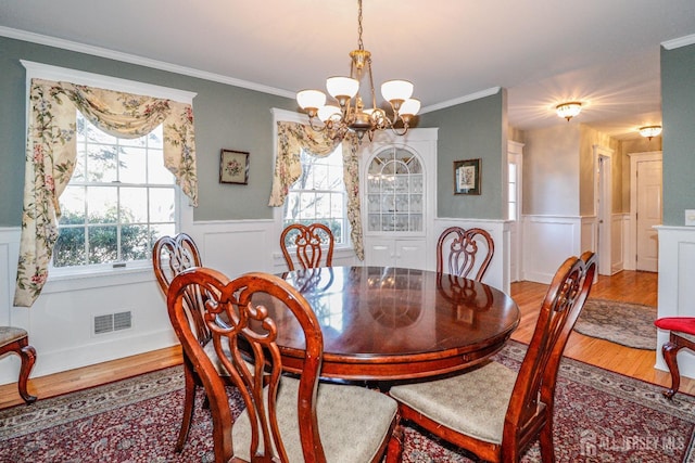 dining space with a notable chandelier, visible vents, a healthy amount of sunlight, and wood finished floors