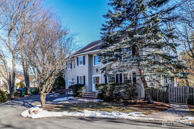 colonial inspired home featuring aphalt driveway and fence