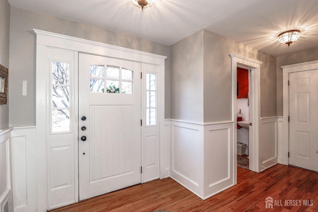 entrance foyer with light wood finished floors and a wainscoted wall