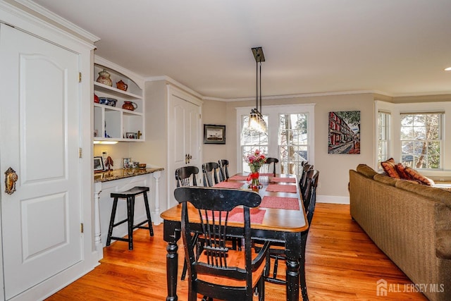 dining area with light wood-style flooring, baseboards, and ornamental molding