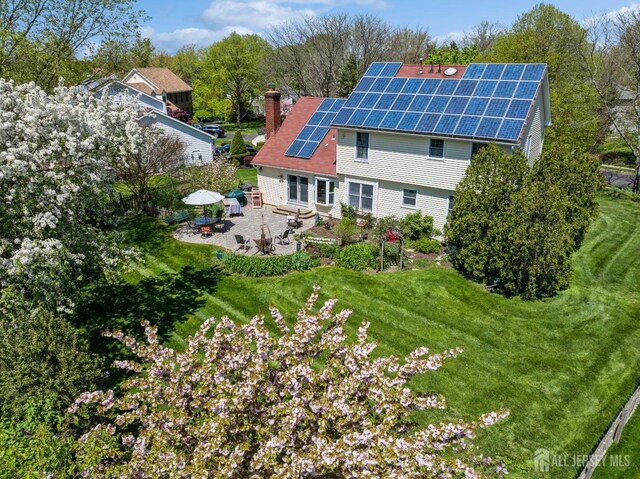 back of property featuring a lawn, a patio, and solar panels