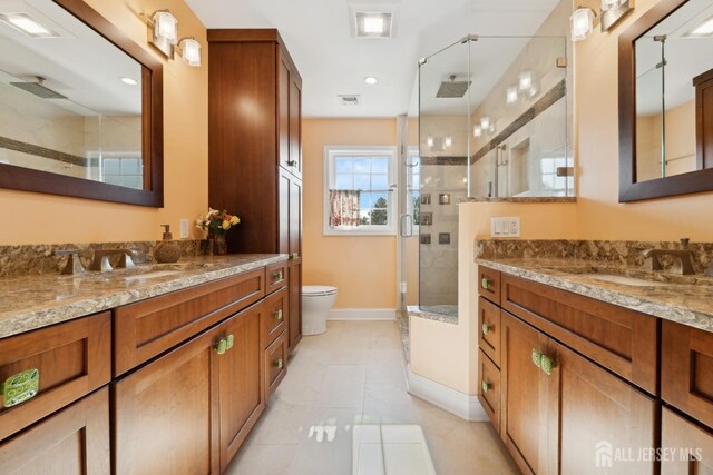 bathroom with vanity, toilet, tile patterned flooring, and a shower with door