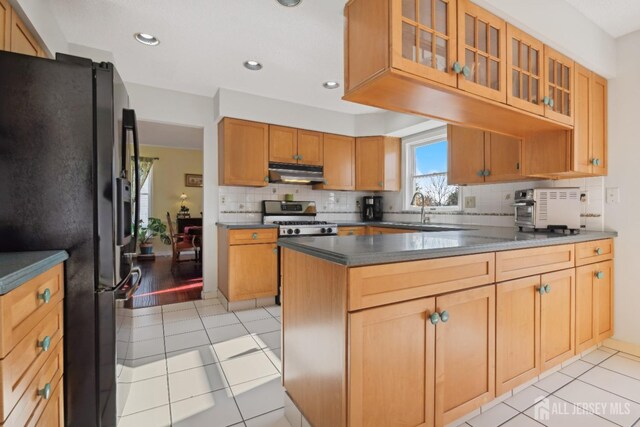 kitchen featuring sink, light tile patterned floors, stainless steel range oven, and black fridge with ice dispenser