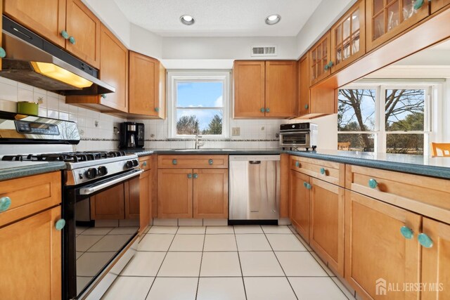 kitchen featuring sink, backsplash, light tile patterned floors, stainless steel appliances, and a textured ceiling