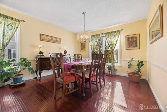 dining room featuring dark wood-type flooring, a textured ceiling, and an inviting chandelier