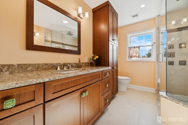 bathroom with a shower with door, vanity, and toilet