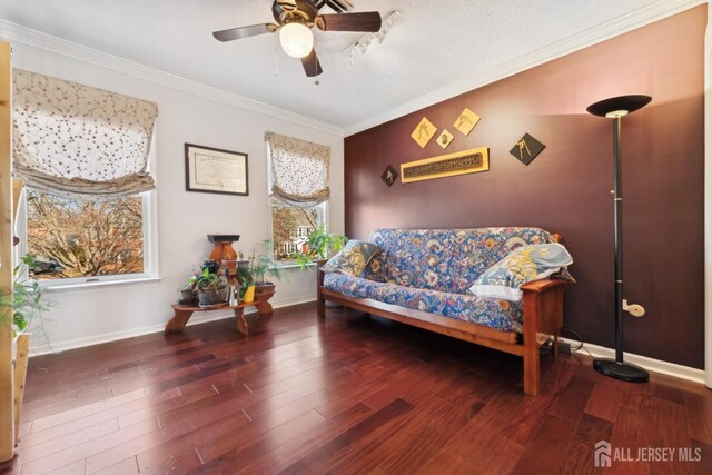 sitting room with dark hardwood / wood-style flooring, crown molding, and ceiling fan