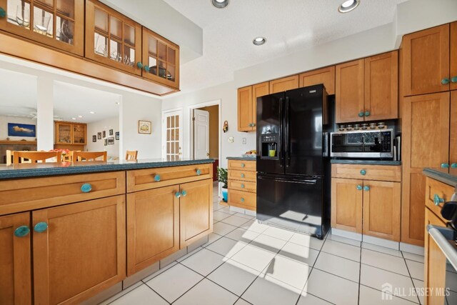 kitchen with black fridge with ice dispenser and light tile patterned flooring