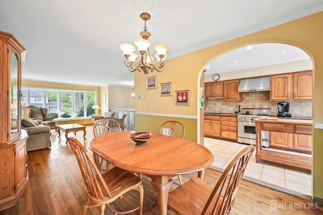 134 Devon Rd, Colonia, NJ 07067 - dining room with a chandelier, light wood-style flooring, and arched walkways