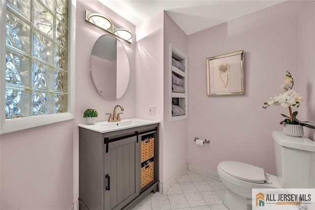 half bath with tile patterned floors, vanity, baseboards, and toilet