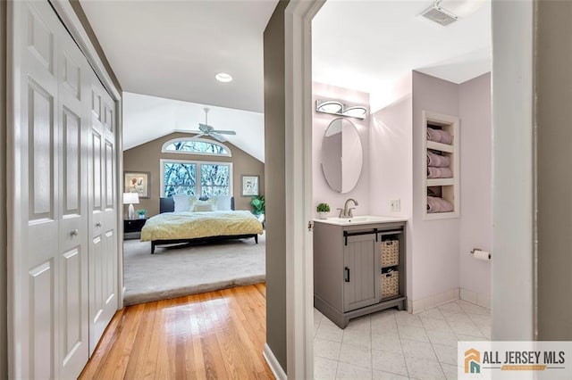 bathroom featuring ceiling fan, visible vents, vaulted ceiling, wood finished floors, and built in shelves