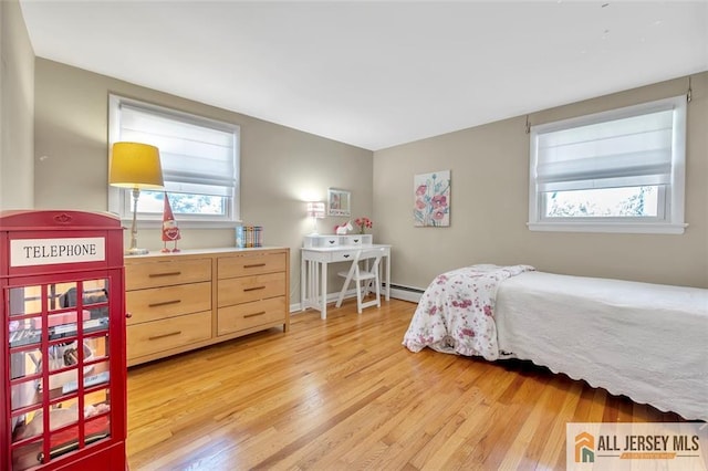 bedroom with light wood-style floors, a baseboard heating unit, and multiple windows