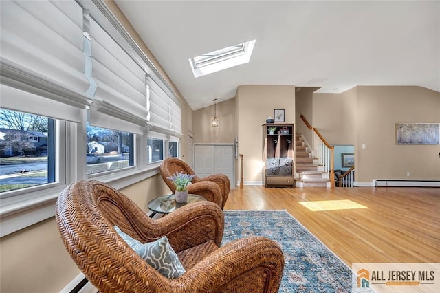 living room with vaulted ceiling with skylight, wood finished floors, baseboards, and stairway