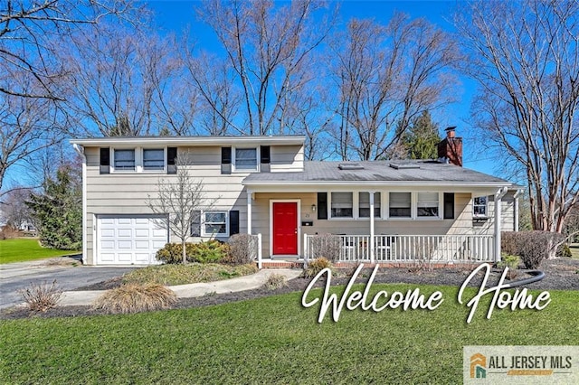split level home with covered porch, a front lawn, an attached garage, a chimney, and driveway