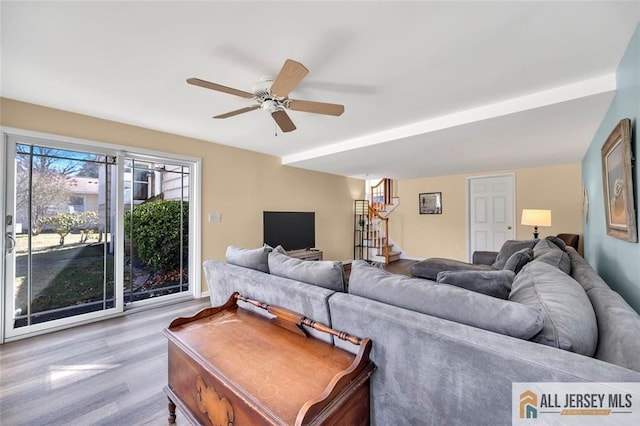 living area with stairway, wood finished floors, and ceiling fan