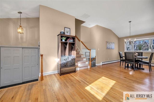 foyer entrance featuring a chandelier, stairway, wood-type flooring, a baseboard heating unit, and lofted ceiling