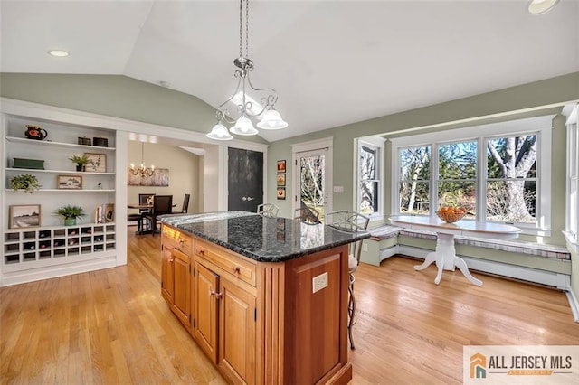kitchen with a kitchen island, an inviting chandelier, light wood-style floors, and lofted ceiling