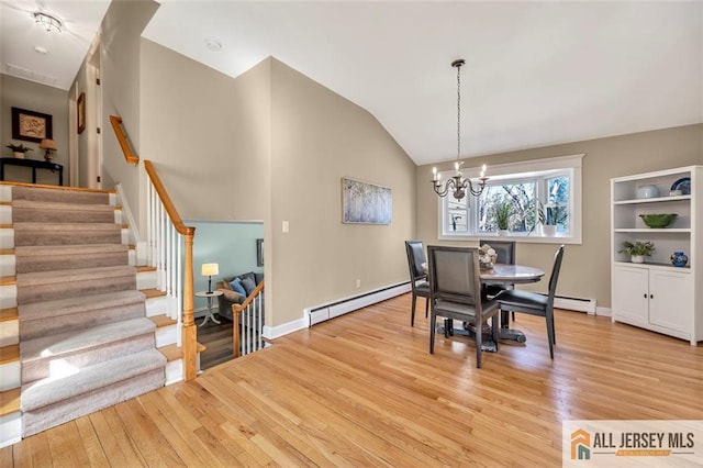 dining space with baseboard heating, an inviting chandelier, vaulted ceiling, stairs, and light wood finished floors