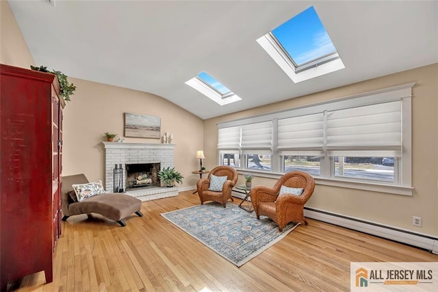sitting room with vaulted ceiling with skylight, a baseboard heating unit, wood finished floors, and a fireplace