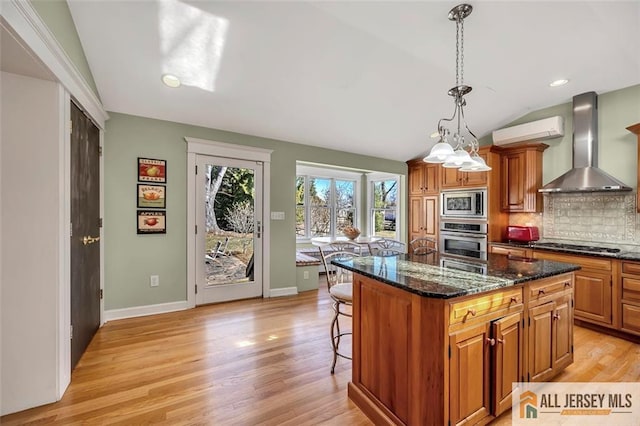 kitchen featuring wall chimney exhaust hood, appliances with stainless steel finishes, a kitchen bar, vaulted ceiling, and decorative backsplash