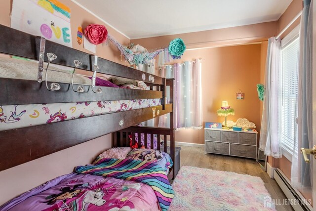 bedroom with a baseboard radiator, baseboards, and wood finished floors