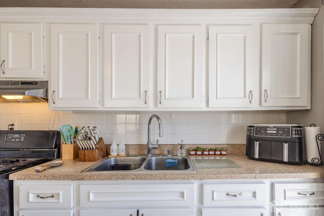 kitchen featuring under cabinet range hood, light countertops, stove, white cabinetry, and a sink