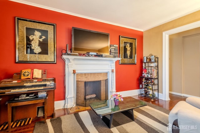 living area with a brick fireplace, wood finished floors, baseboards, and ornamental molding