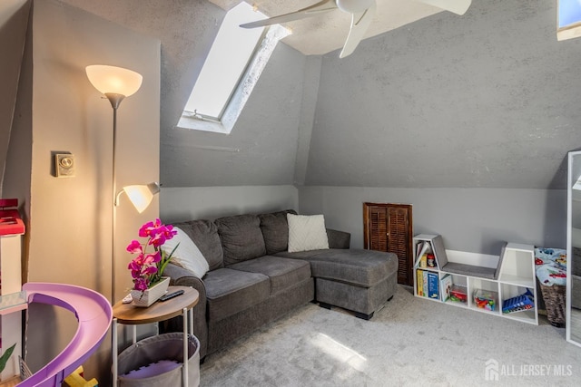 living area featuring a textured ceiling, vaulted ceiling with skylight, carpet flooring, and ceiling fan