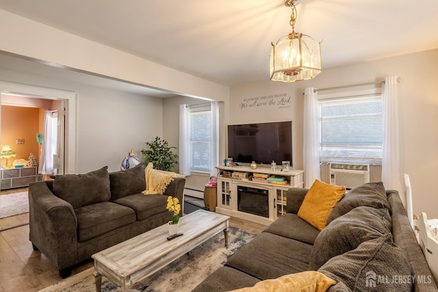 living room featuring wood finished floors, baseboard heating, and a healthy amount of sunlight