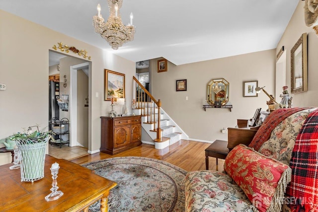 living area featuring a chandelier, light wood-style flooring, baseboards, and stairs