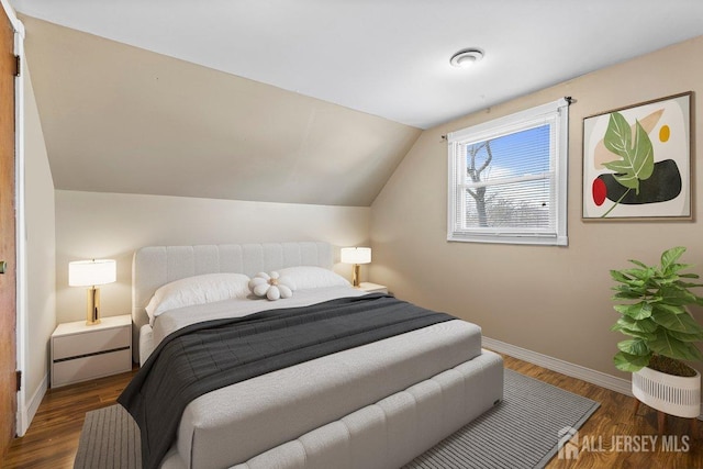 bedroom featuring lofted ceiling, dark wood-style flooring, and baseboards